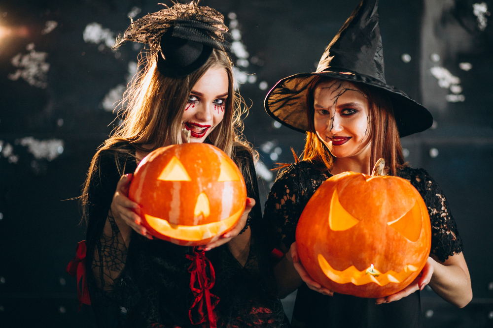 duas meninas vestidas de bruxas segurando abóboras
