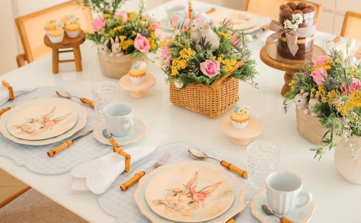 mesa posta de páscoa com arranjo florido, guardanapos, talheres, xícaras e aparelho de jantar temático