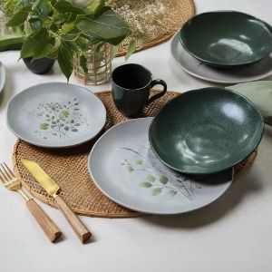 Mesa posta com destaque para pratos e caneca verdes.