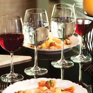 Mesa posta com pratos servidos e quatro taças cheias de água e vinho