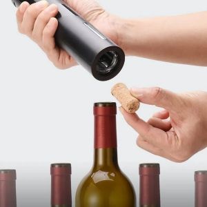 Mãos masculinas usando abridor de vinho elétrico.