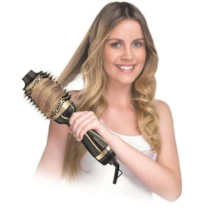 Mulher loira e sorridente usando escova secadora nos cabelos.