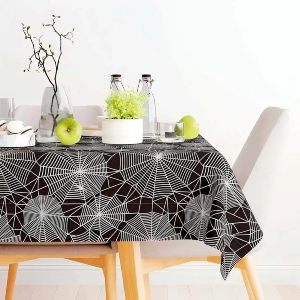 Mesa de jantar com toalha preta com estampa de teia de aranha.