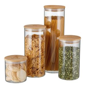Quatro potes de vidro de tamanhos diferentes, com mantimentos dentro e com tampa de bambu.