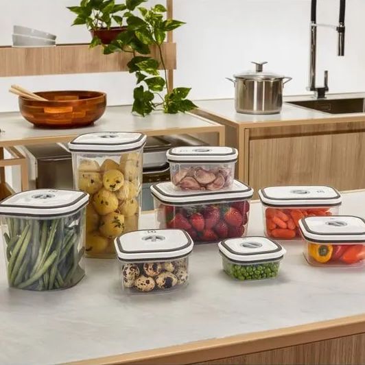 Bancada de cozinha com potes herméticos de diferentes tamanhos cheios de alimentos frescos.