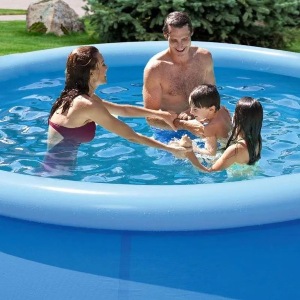 Homem, mulher e duas crianças, sendo um menino e uma menina, brincando em piscina inflável.