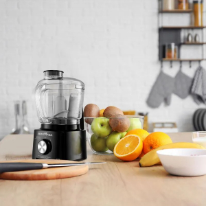 Bancada de cozinha com processador de alimentos ao lado de bowl com frutas.