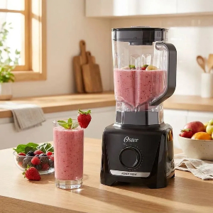 Liquidificador com suco de morango ao lado de copo também com copo.